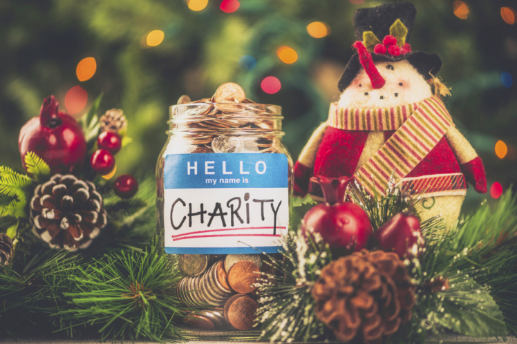 Charity donation jar filled with American currency in holiday setting